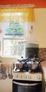 zwei Töpfe auf einem Herd in einer Küche mit Fenster in der Unterkunft "SunRise Inn" Nature Island Dominica 