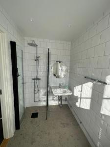 a white tiled bathroom with a sink and a shower at Crusellska Vandrarhemmet in Strömstad