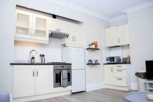 a white kitchen with white cabinets and a stove at Reading Spacious Stay, NHS & Contractors in Reading