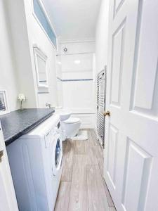 ein weißes Bad mit einer Waschmaschine und einem WC in der Unterkunft Reading Spacious Stay, NHS & Contractors in Reading