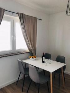 a dining room table with chairs and a bottle of wine at Apartman DE in Velika Gorica