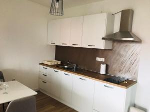 uma cozinha com armários brancos, um lavatório e uma mesa em Apartman DE em Velika Gorica