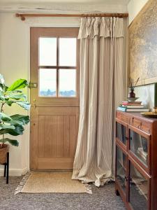 a door with curtains and a window in a room at Charming 3 bedroom house in Woodbridge area in Grundisburgh