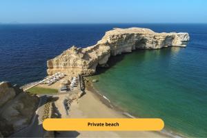 un'immagine di una spiaggia con una grande formazione rocciosa di Shangri-La Al Husn, Muscat - Adults Only Resort a Mascate