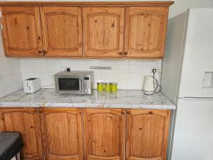 una cocina con armarios de madera y microondas en una encimera en VIKKY LODGE en Birmingham