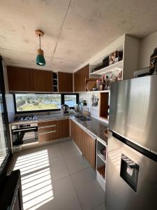 una cocina con nevera de acero inoxidable y armarios de madera en Apartamento frente al lago, en Montevideo