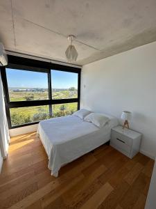 a bedroom with a bed and a large window at Apartamento frente al lago in Montevideo