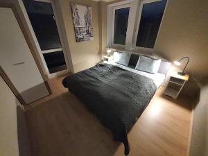 a bedroom with a large bed and two windows at JDK Apartamenty Legionów 74m2 8-osobowy in Kalisz