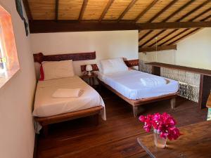 um quarto com duas camas e um vaso de flores em Casa Vagalume - 10 minutes to secluded beach em Pôrto de Pedras