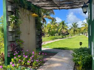um arco que leva a um jardim com flores e palmeiras em Casa Vagalume - 10 minutes to secluded beach em Pôrto de Pedras