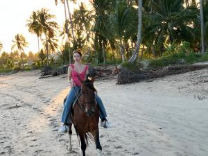 uma mulher montada num cavalo na praia em Casa Vagalume - 10 minutes to secluded beach em Pôrto de Pedras
