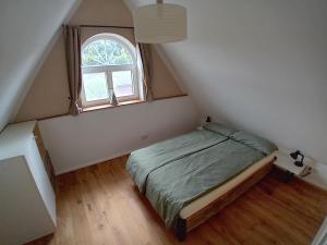 um quarto com uma cama e uma janela no sótão em Ferienhaus am Kuhstall em Bad Münstereifel