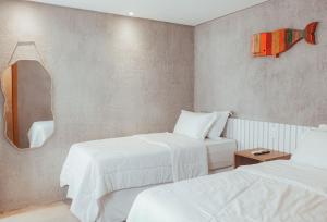 Cette chambre comprend 2 lits et un miroir. dans l'établissement Triplex Temporada Areia e Mar Patacho - Casa Verde, à Porto de Pedras