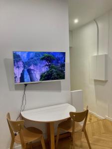 a white table with two chairs and a tv on a wall at Appartement confortable et complet in Clichy