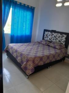 1 dormitorio con 1 cama con cortinas azules y ventana en Casa vacacional Honda Tolima, en Honda