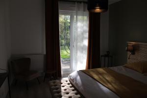 1 dormitorio con cama, ventana y silla en Le pré du buis, en Yvré-lʼÉvêque