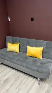a gray couch with two yellow pillows on it at Батыс in Aktobe