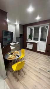 a living room with a table and yellow chairs at Батыс in Aktobe