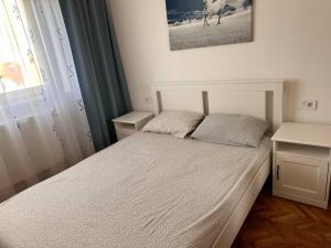 a bedroom with a white bed with a picture on the wall at Lux Apartment Vivo Mall in Baia Mare