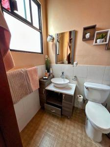 La salle de bains est pourvue de toilettes blanches et d'un lavabo. dans l'établissement Casa de las Palmas Guest House, à Oaxaca