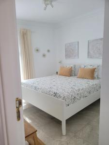 Cama blanca en habitación blanca con almohadas en Realidad, en Playa Blanca