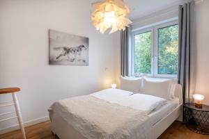 1 dormitorio con cama blanca y lámpara de araña en Mado, en Władysławowo