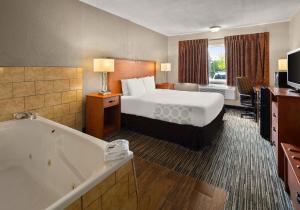 a hotel room with a bed and a bath tub at Magnuson Hotel Detroit Airport in Romulus