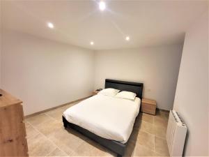 a bedroom with a bed with white sheets and pillows at Joli T2 1er étage wifi/verdon/centre ville in Castellane