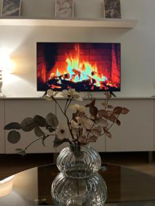 a glass vase with flowers in front of a fireplace at Amot apartamentai in Telšiai