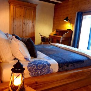a bed with a blue and white comforter and a lamp at Rouet Nature in Tréban