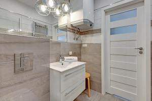 a white bathroom with a sink and a door at BALTIC PARK A Apartamenty PIAMOLA in Stegna