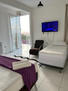 um quarto com 2 camas, uma cadeira e uma televisão em SUITE ELEGACY em Serra de São Bento