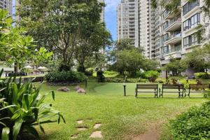 a park with benches in the grass and buildings at Lovely Apartment in Colombo - Havelock City in Colombo