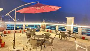 a patio with tables and chairs and an umbrella at Hotel Mountain Meadows in Manāli