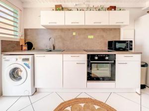 a kitchen with a washing machine and a microwave at Plage 37 Orient Bay beach front with pool access in Orient Bay