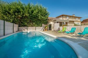 a swimming pool with two chairs and a house at Villa de 4 chambres avec piscine privee jardin amenage et wifi a Courrensan in Courrensan