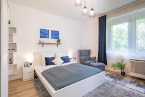 um quarto branco com uma cama e uma cadeira em Cozy Home - Close to River - Easy Parking em Budapeste