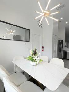 a white dining room with a white table and white chairs at Luxury Modern Pool House close to theme parks. in Kissimmee
