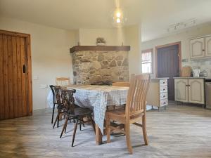 une table et des chaises dans une cuisine avec un mur en pierre dans l'établissement Longford Holiday Red Rose Self Catering Cottage, à Longford