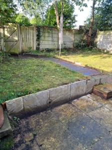 a retaining wall in a yard with a fence at Stonebarn Lane One Bed in Halton