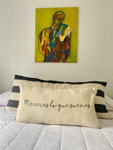 a painting above a bed with a white pillow at Deptos Tuc in San Miguel de Tucumán