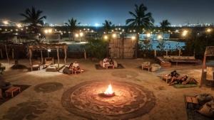 a group of people sitting around a fire pit at night at Fenix Beach Cartagena in Tierra Bomba