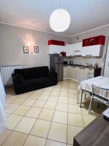 ein Wohnzimmer mit einem schwarzen Sofa und einer Küche in der Unterkunft Appartamento Essenza in Sirmione