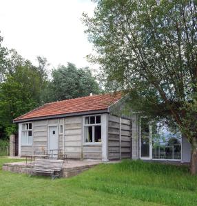 a small wooden cabin with a bench in a yard at Barak de Vinck in Ypres