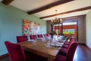 uma sala de jantar com uma longa mesa de madeira e cadeiras vermelhas em Luxo e Conforto na Praia de Cotovelo por Carpediem em Parnamirim