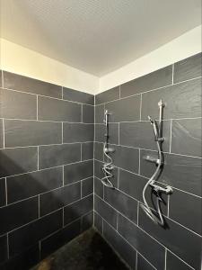 Baño de azulejos negros con 2 perchas en la pared en La Villa Bacchus en Groslée