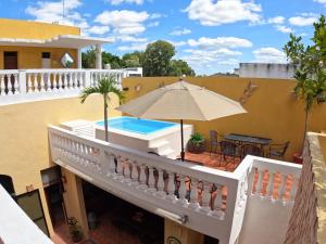 einen Balkon mit Sonnenschirm und Pool in der Unterkunft Hotel del Peregrino Boutique Hotel in Mérida
