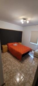 een slaapkamer met een bed met een oranje dekbed bij Departamento mendoza ciudad in Mendoza