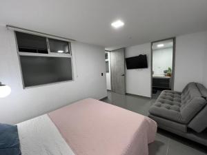 ein Schlafzimmer mit einem Bett, einem Stuhl und einem TV in der Unterkunft El mirador paisa in Bello