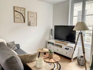 uma sala de estar com um sofá e uma televisão de ecrã plano em L'Hippolyte - Cœur de ville em Compiègne